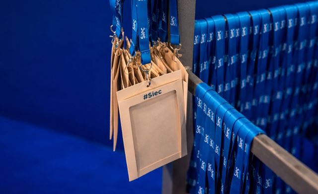 Siec visitor badges hanging on a rack with blue lanyards.
