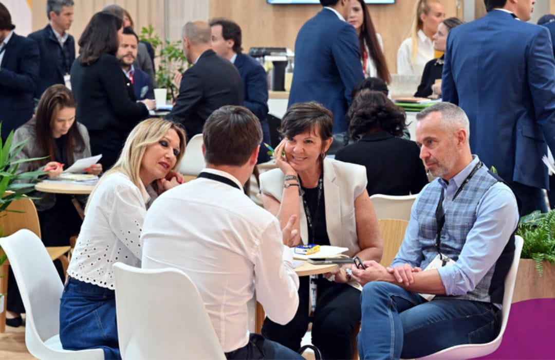 Professionnels échangeant lors d’une rencontre d’affaires sur un salon, dans une ambiance conviviale.