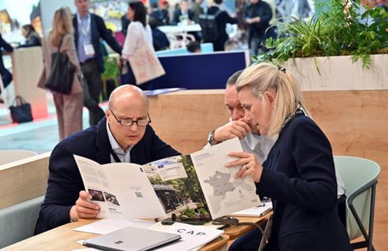 Trois professionnels analysant un document stratégique lors d’un rendez-vous au salon.