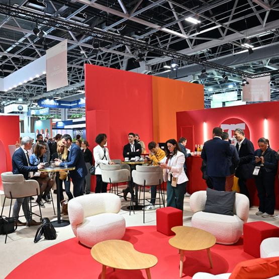 Professionnels en plein networking sur un salon B2B dans un espace lounge design et coloré, ambiance conviviale.